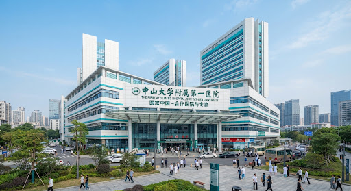 Modern architectural exterior view of The First Affiliated Hospital of Sun Yat-sen University in Guangzhou, China on a clear bright day with medical pavilion entrance and clinical towers in white and cyan accents.